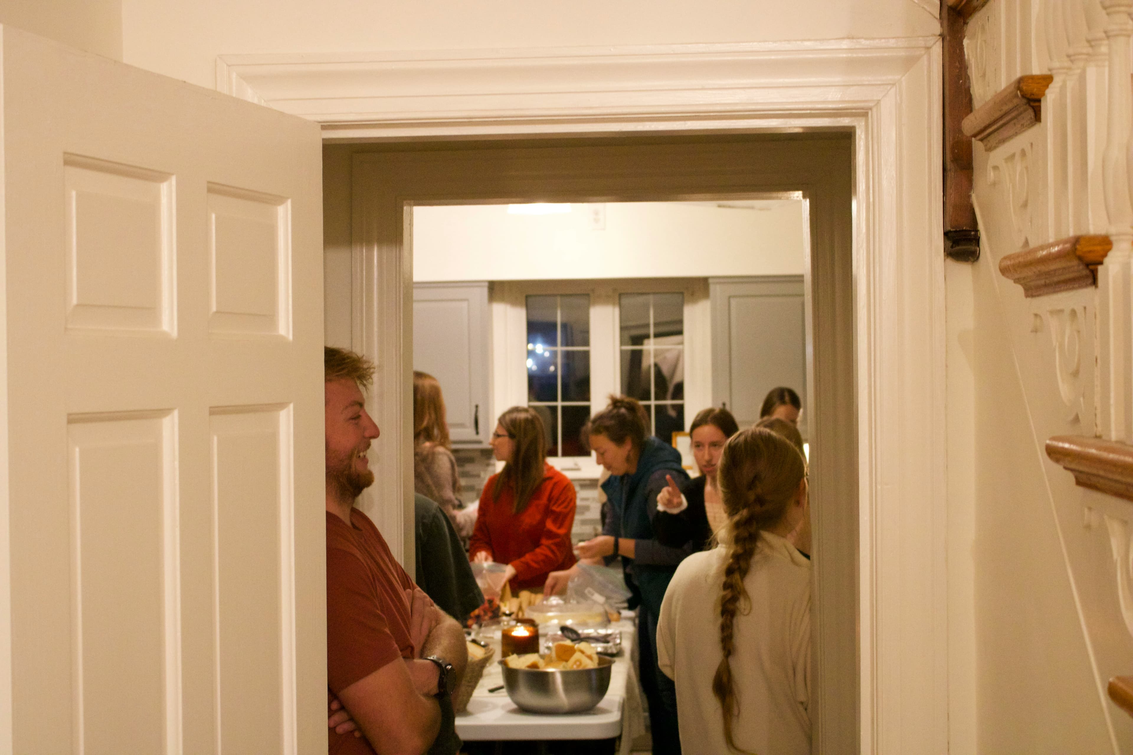A group of people preparing food together in a kitchen, seen through an open doorway