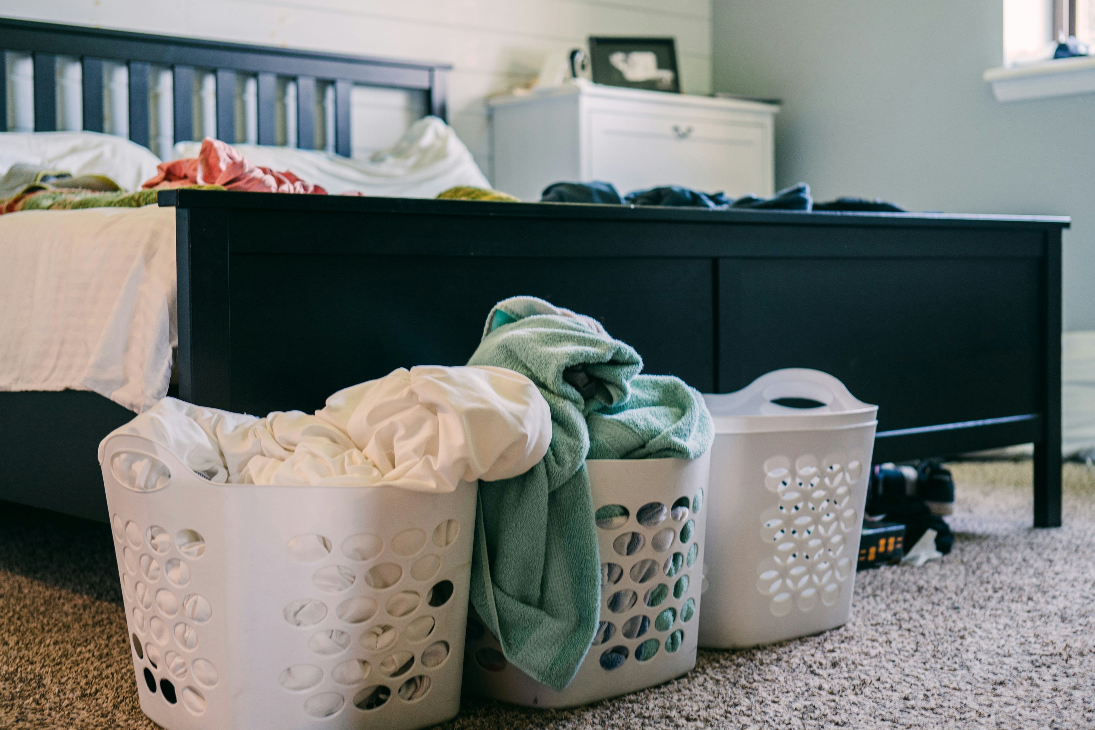 Laundry baskets full of towels and sheets at the foot of a bed